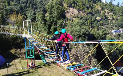 People crossing a rope bridge adventure course at the camp site